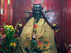 16C A statue covered in an embroidered cloak with incense and flower offerings at Lit Shing Kung, part of Man Mo Temple Hong Kong